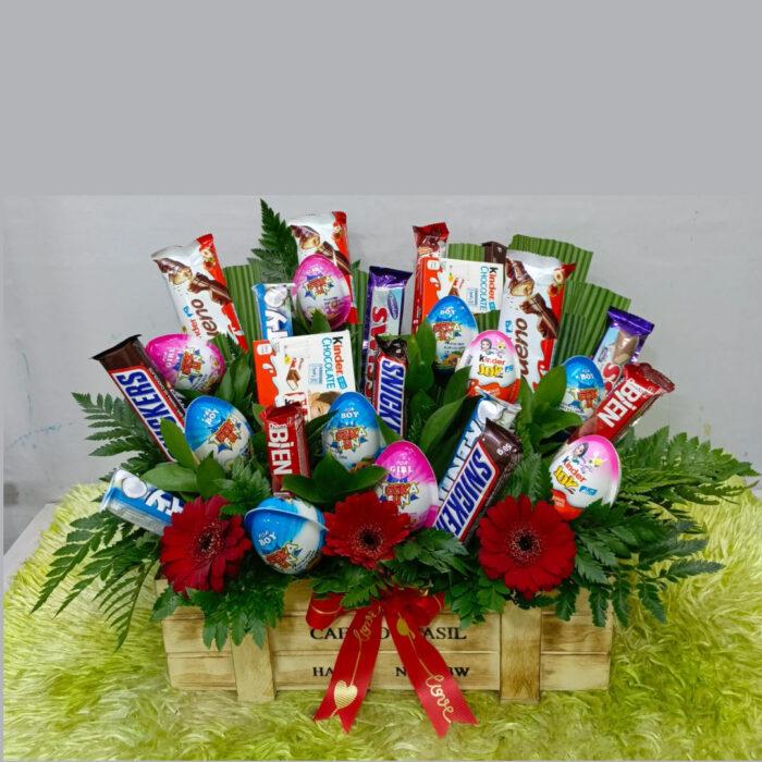 Chocolate flower hamper with assorted candy bars and floral arrangement in a gift crate
