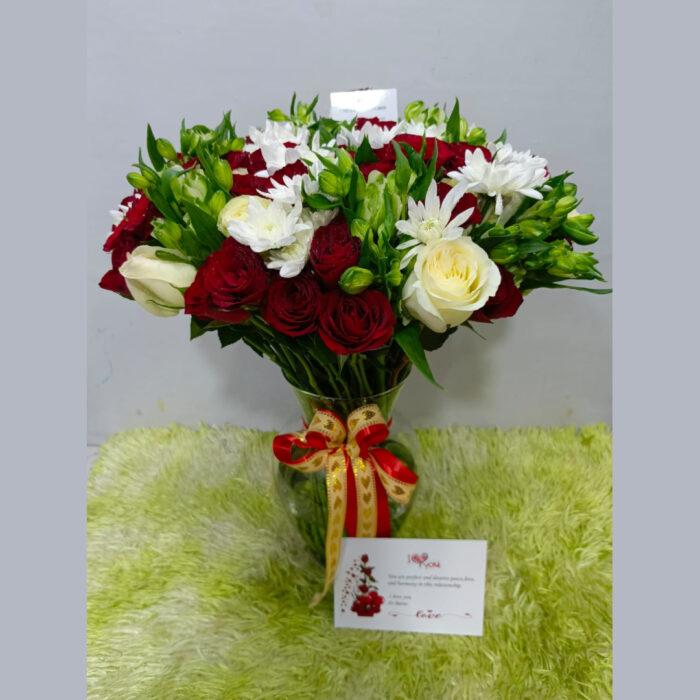 Vase flower arrangement with red and white roses and decorative ribbon