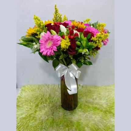 Radiant mixed flower vase arrangement with gerberas, roses, and sunflowers in a glass vase